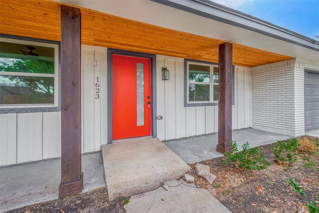An inviting covered porch showcases a cedar-toned ceiling, dark timber posts, and a bold red door—setting a stylish, modern tone before you even step inside.