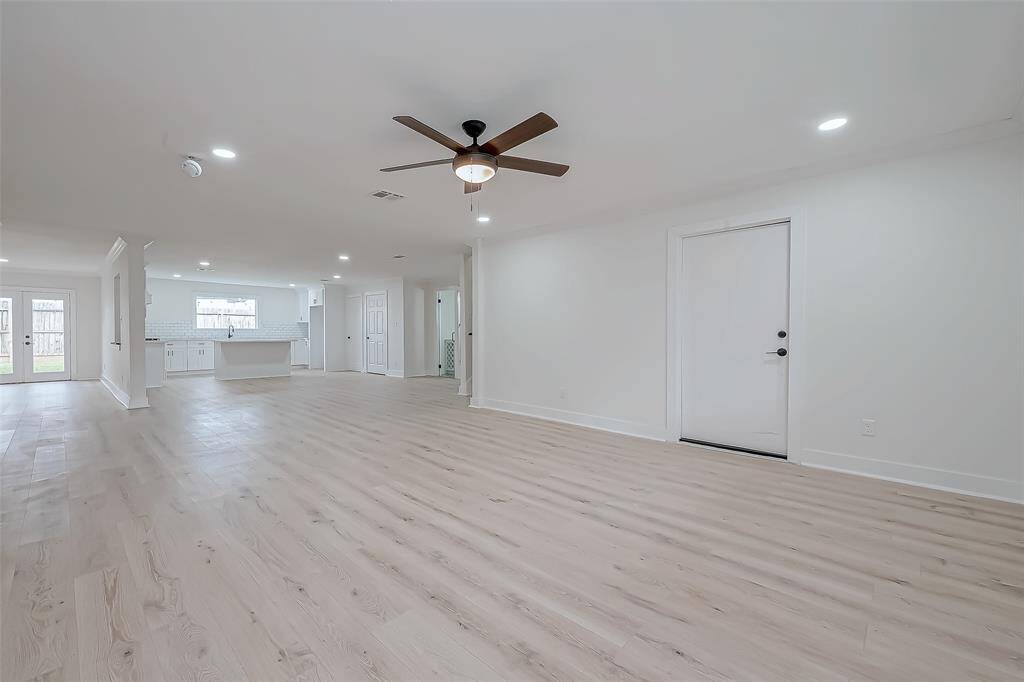 Expansive open-concept living area showcases wide-plank hardwood floors, fresh designer paint, recessed LED lighting, and effortless flow into the sleek kitchen—an entertainer’s dream space.
