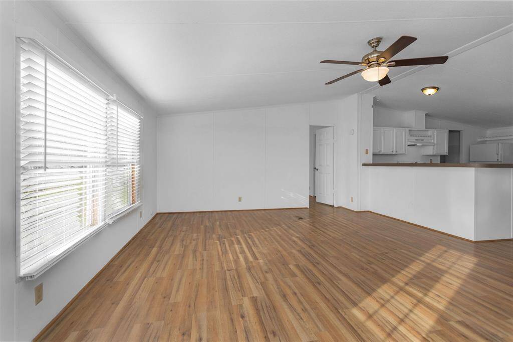 Living room has ceiling fan and wall of windows to the front yard