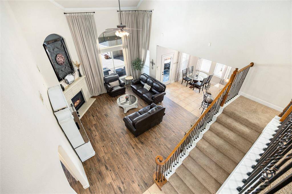 An open layout connects the living room to a dining space, creating a warm and inviting atmosphere. Large windows bring in natural light, and a staircase leads to the upper level.