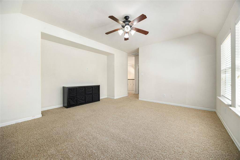 Bright, spacious room with neutral carpet, a ceiling fan, and large windows for natural light.