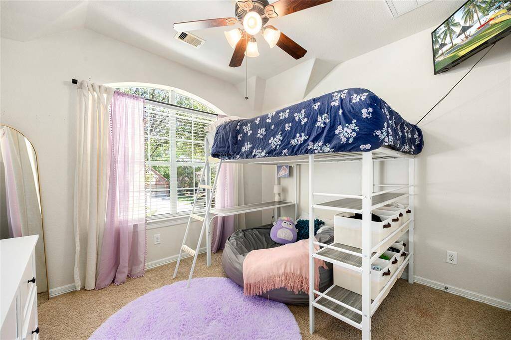 Bright and cozy bedroom with a large window and a ceiling fan.