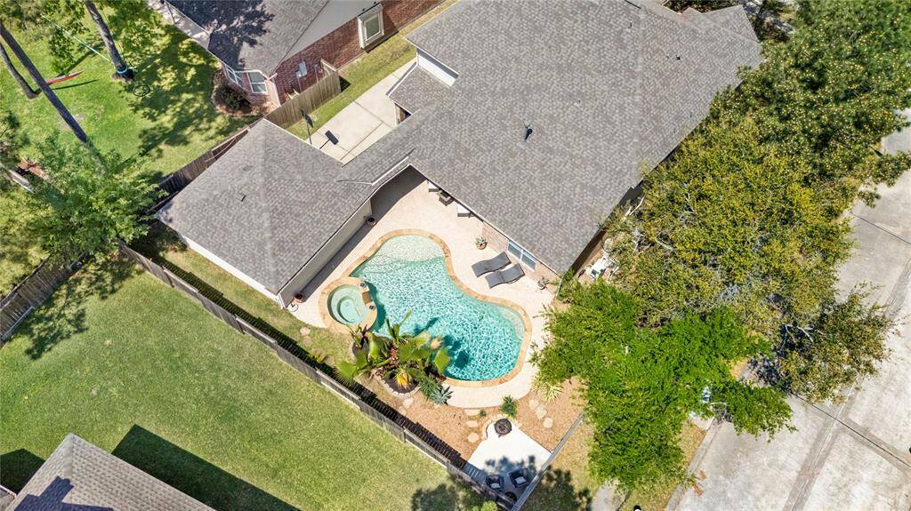This aerial photo showcases a 2 story home with a spacious backyard featuring a beautifully landscaped pool and patio area. The yard is fenced, providing privacy and ample space for outdoor activities.