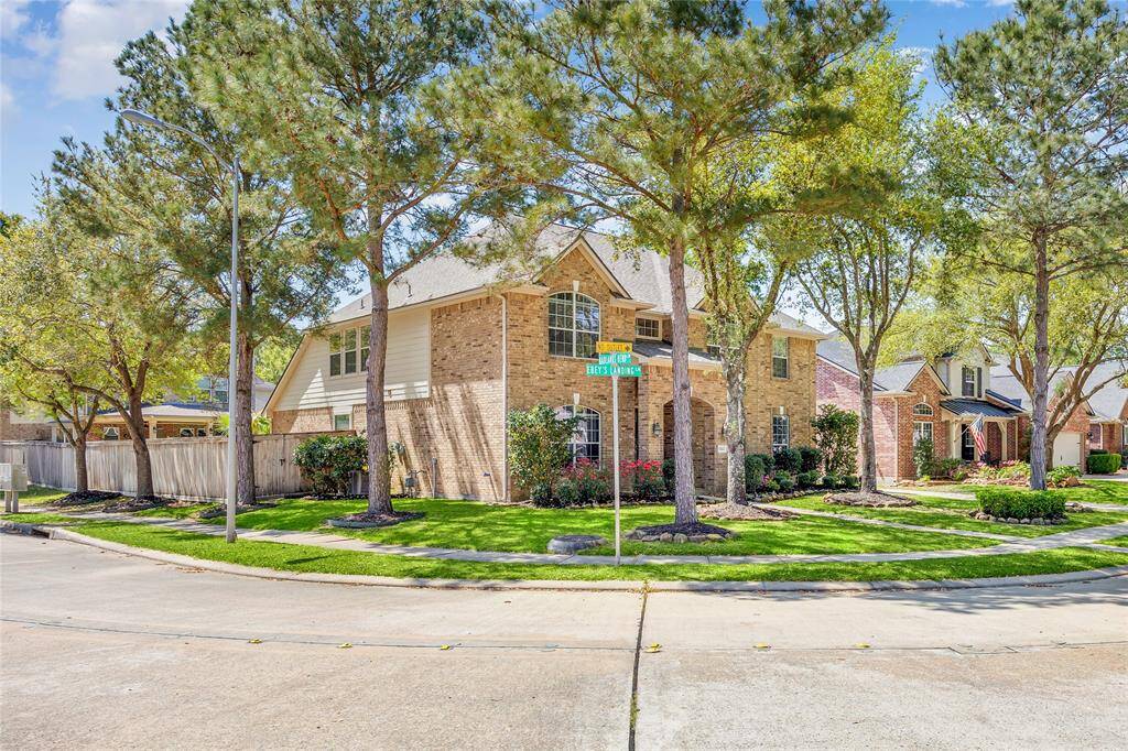 This photo showcases the home on a corner lot, surrounded by mature trees and well-maintained landscaping.
