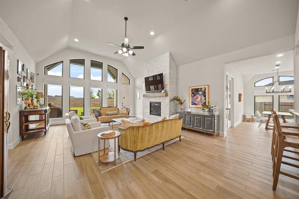 Inviting Family Room features wood-look tile floors, vaulted ceilings, large windows that flood the space with natural light & an upgraded crushed granite Fireplace that serves as a warm & inviting focal point.