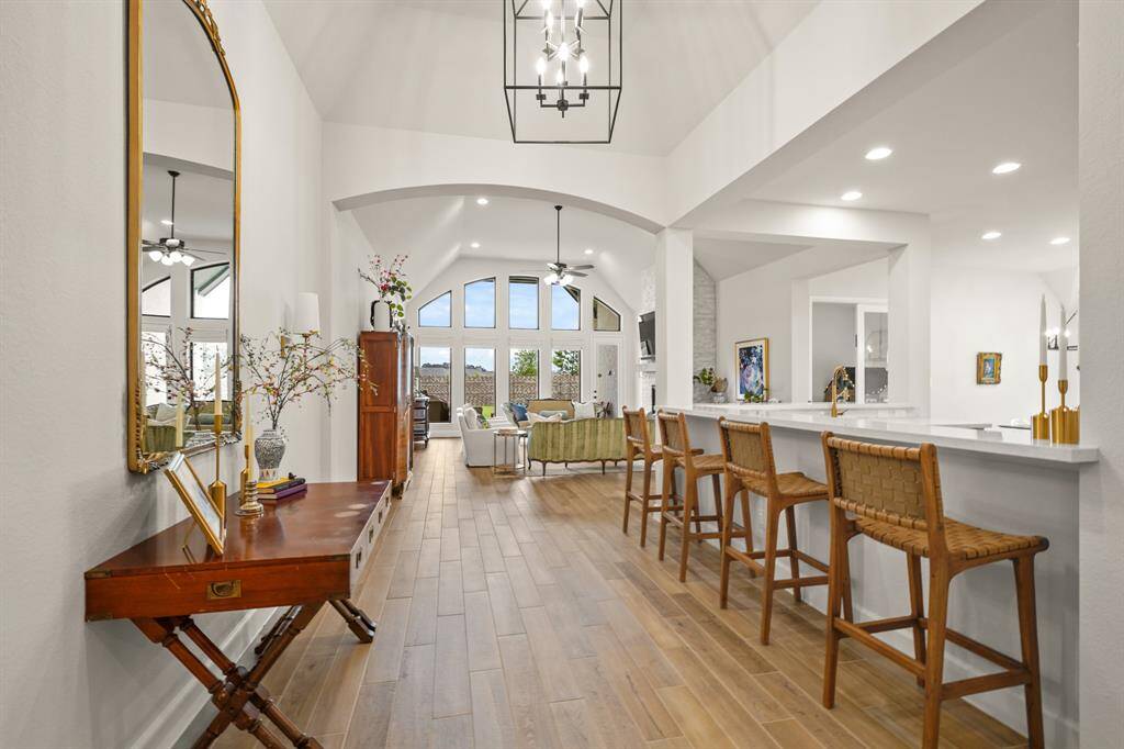 This beautifully designed open-concept space features a bright & airy space featuring wood-look tile flooring, a large breakfast bar, vaulted ceilings, & lots of natural light.