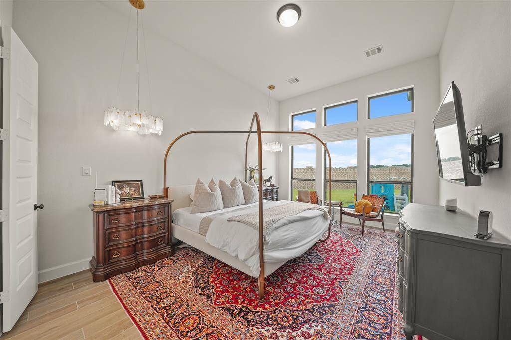 The Primary Bedroom offers a bright, airy retreat with high ceilings, large windows, motorized Roman shades, & elegant Cloud Glass Chandeliers — complete with a private En Suite Bathroom.