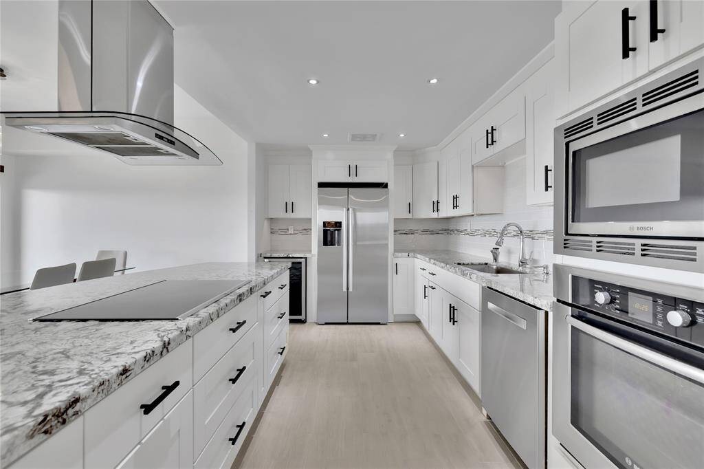 The view from the kitchen facing the dining room and outdoor balcony. Check out all the kitchen cabinetry and the exhaust fan located above the stovetop.