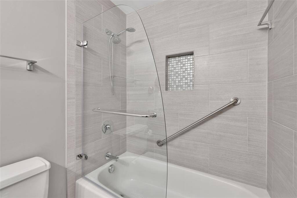 The second bathroom is a bathtub/shower combo with neutral tile. Notice the shower niche to neatly store shampoo and soap.