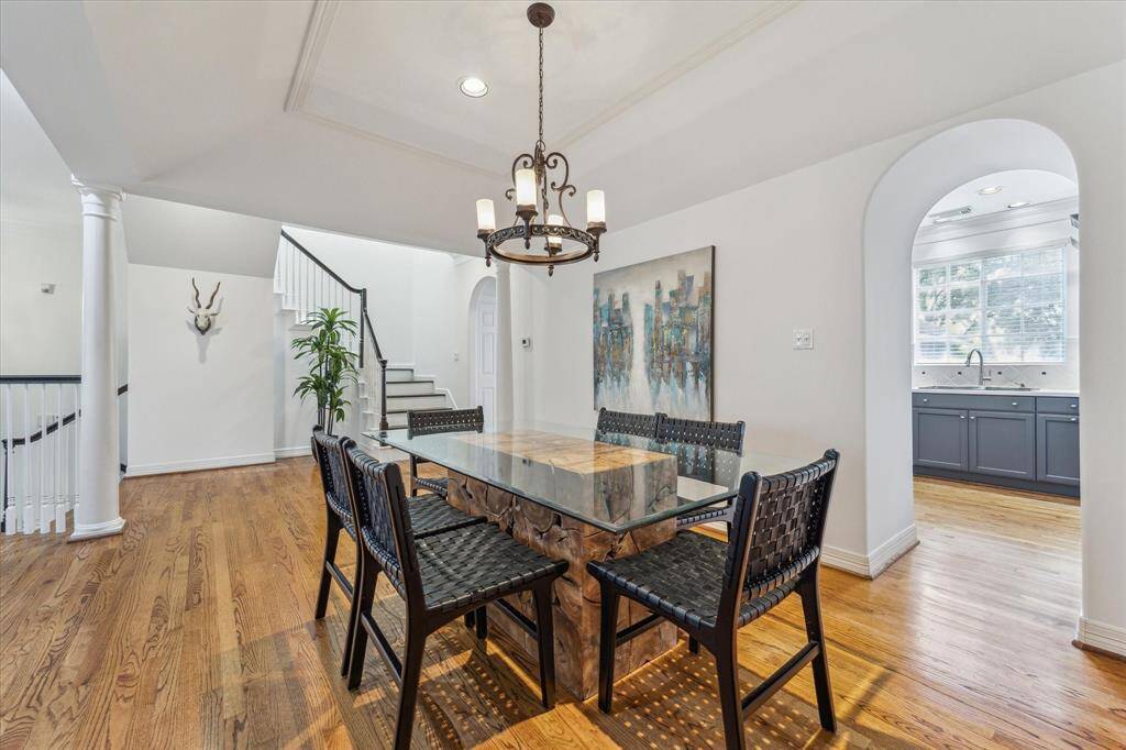 Dining room with hardwood floors, chandelier, recessed lighting, tray ceiling and crown molding.