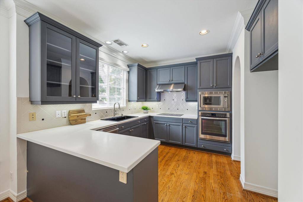 Kitchen with hardwood floors, recessed lighting, crown molding and stainless steel appliances.