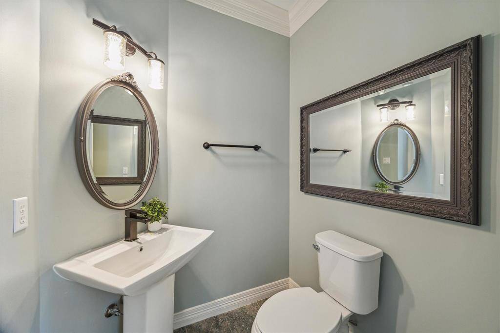This powder bath features a pedestal sink, framed mirror, and elegant lighting.