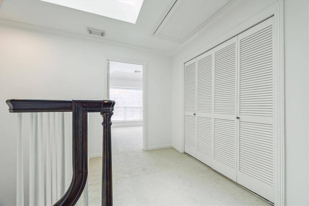 The upper landing is bright and welcoming, featuring louvered doors to the utility closet and access to the primary and secondary bedroom.