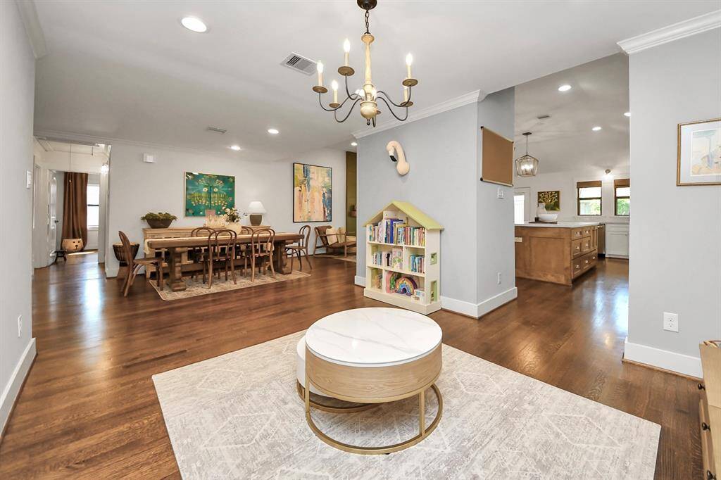 This inviting open-concept space features hardwood floors and ample natural light. It includes a spacious dining area, cozy sitting nook, and a modern kitchen with wooden cabinetry. Perfect for family gatherings and entertaining.