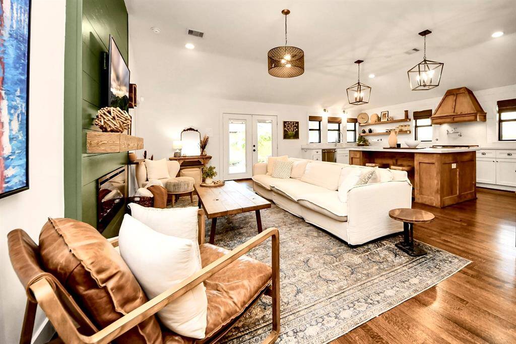 Experience the charm of this open-concept living area featuring a modern kitchen, hardwood floors, and stylish lighting. Perfect for relaxation and entertaining.