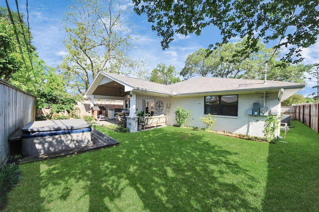 Spacious backyard featuring a relaxing hot tub, green space, mosquito misting system, sprinkler system, and French drains for easy maintenance and comfort year-round.