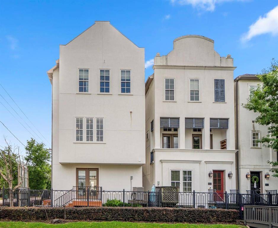 Elegant corner townhome with modern stucco exterior, private front entrance, and abundant natural light from tall windows—urban living with style and space.