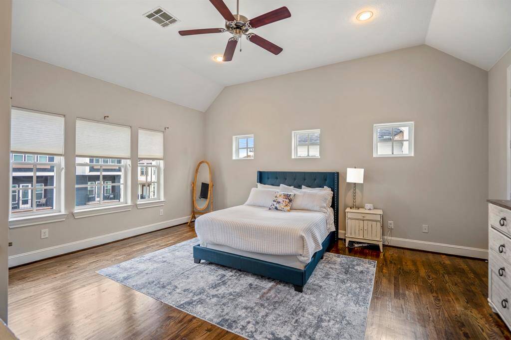 Spacious primary bedroom with vaulted ceiling, hardwood floors, and tons of windows.