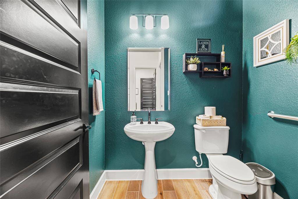 Conveniently located powder room for guests with sleek pedestal sink and sophisticated light fixture.