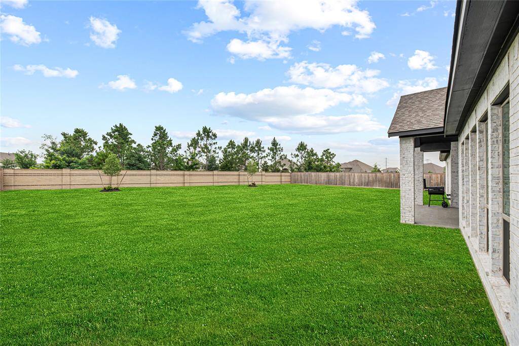 Enjoy outdoor living on the spacious covered patio featuring vaulted ceiling and a scenic view of the large, private backyard—perfect for relaxing or entertaining.