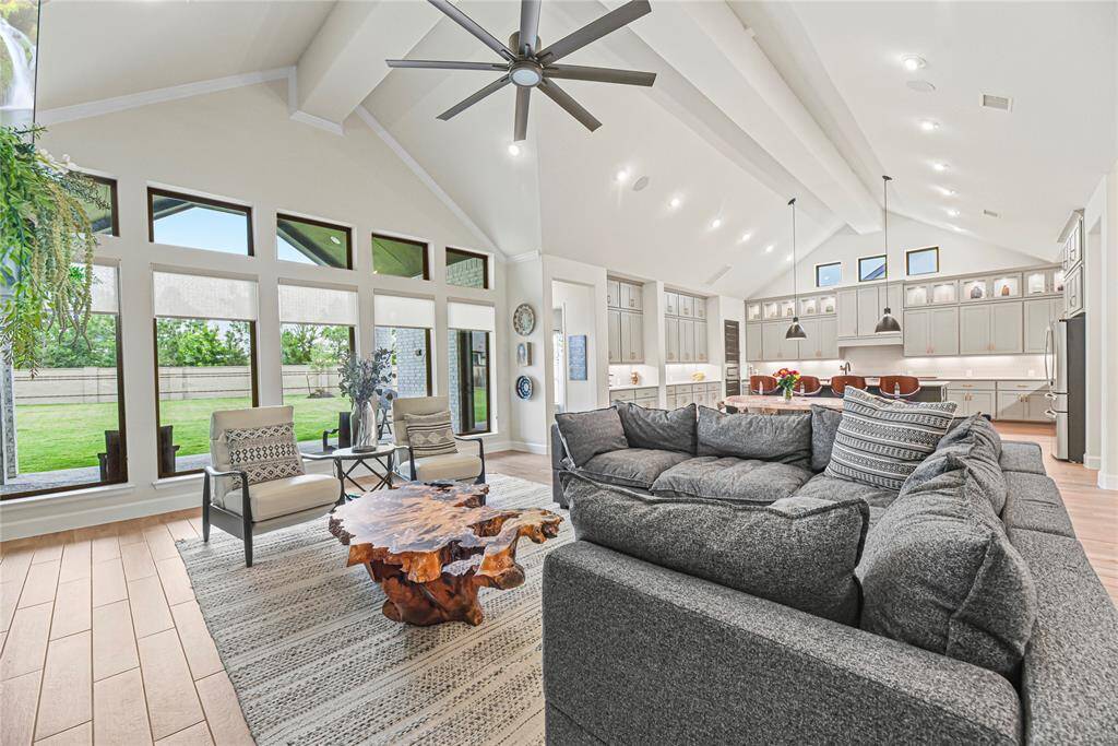 This cozy yet expansive living area showcases a floor-to-ceiling brick fireplace with a built-in mantel and elevated ceilings with crown molding.