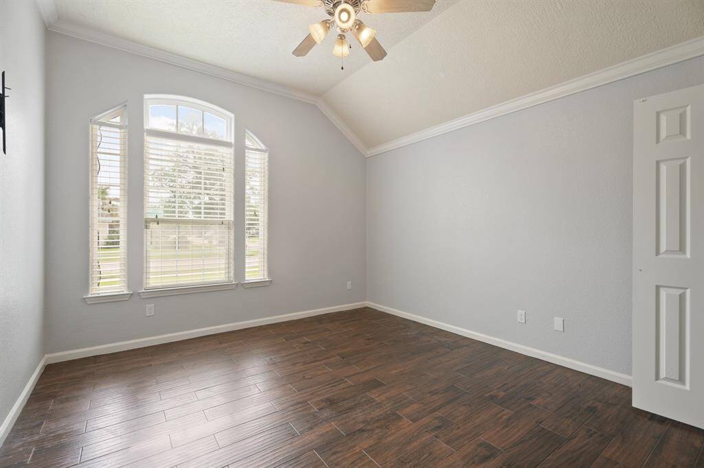 Bright, airy room with vaulted ceiling, wood-style flooring, and large windows offering plenty of natural light. Perfect for a bedroom or home office.