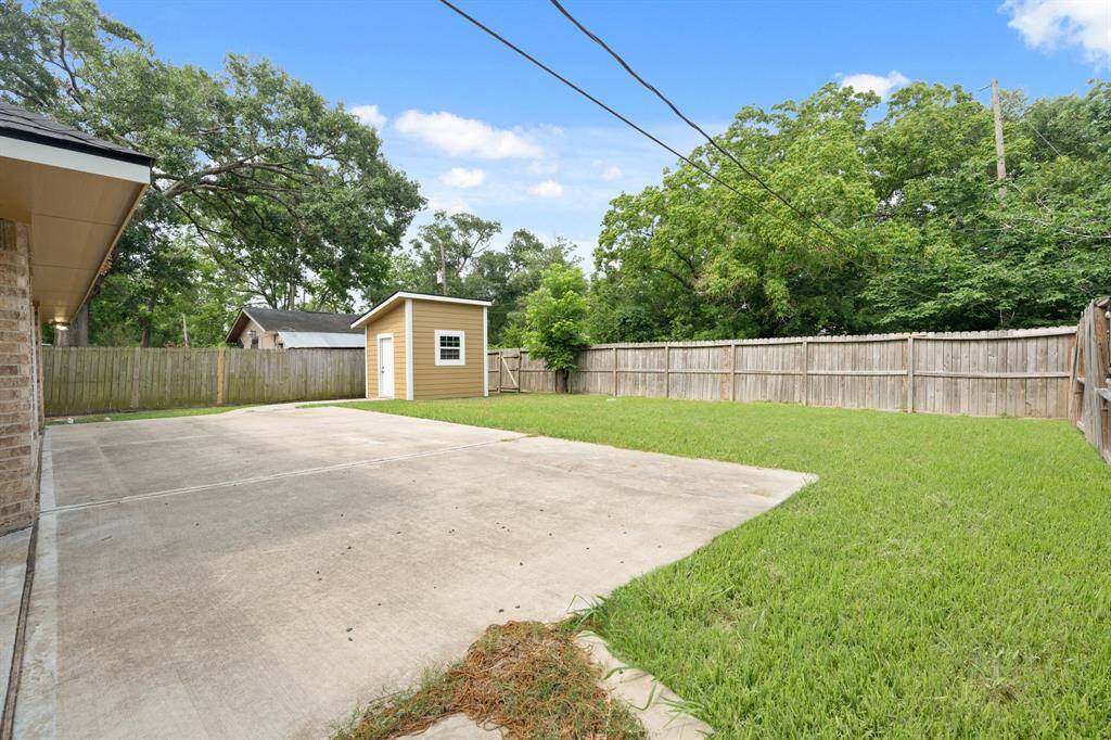 Spacious backyard with a concrete patio area, a small shed, and a well-maintained lawn, all enclosed by a wooden fence for privacy.