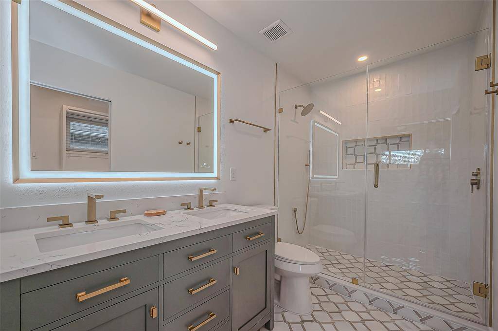 Relax in the newly renovated primary bathroom, featuring a spacious glass-enclosed shower and double sinks for a touch of modern luxury.
