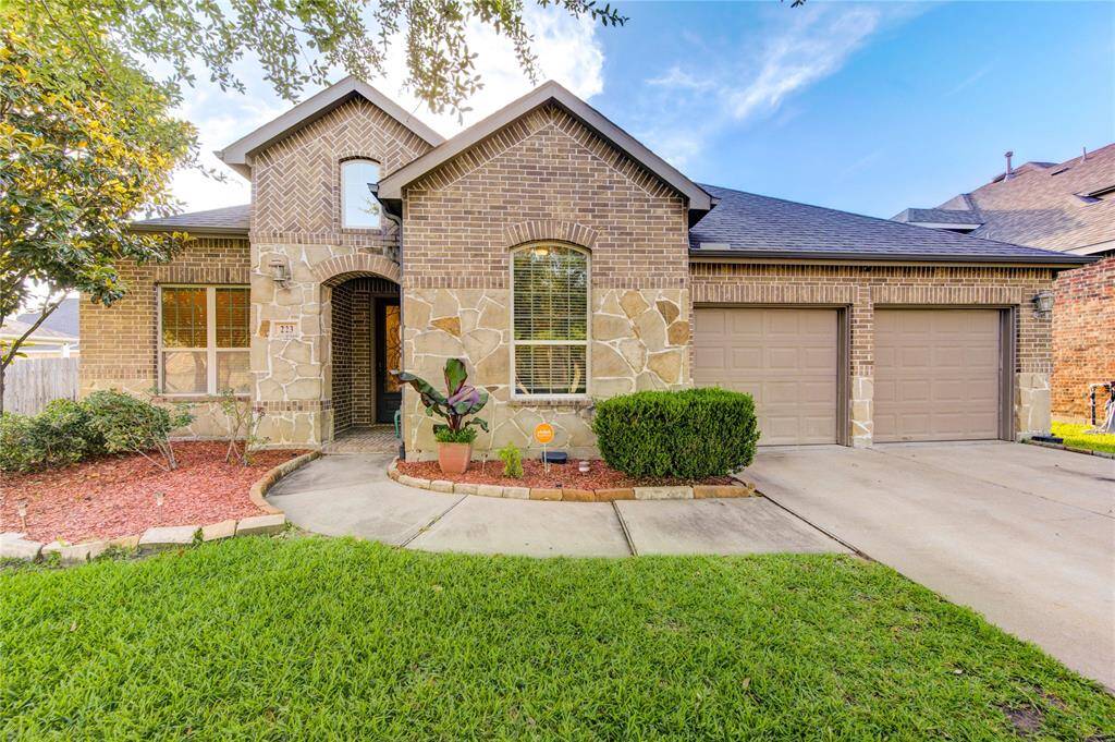 Charming brick and stone exterior home with great curb appeal. Features a well-maintained lawn, landscaped garden beds, and a double garage. The entrance is inviting with a curved walkway and mature trees providing shade. Ideal for families seeking a welcoming neighborhood setting.
