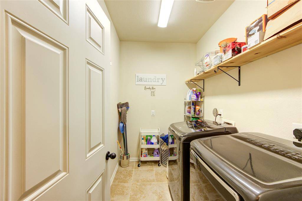 This photo showcases a well-organized laundry room featuring modern appliances, ample storage with shelves, and a tidy arrangement of cleaning supplies. The space is efficiently designed with a clean, bright atmosphere.