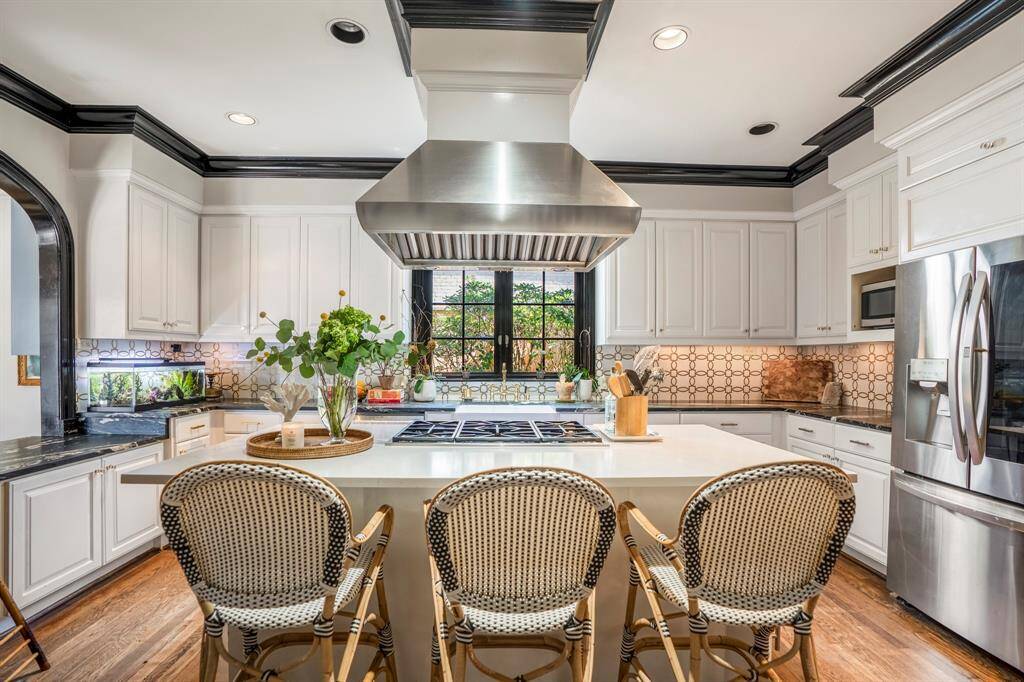 The expansive kitchen island serves as the heart of the space, offering ample prep room, casual seating, and a stylish focal point for gathering and entertaining.