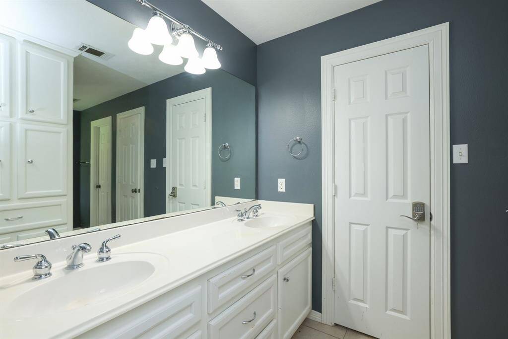 This bathroom features a sleek, white corner bathtub with modern fixtures, complemented by dark walls and a frosted window for privacy.
