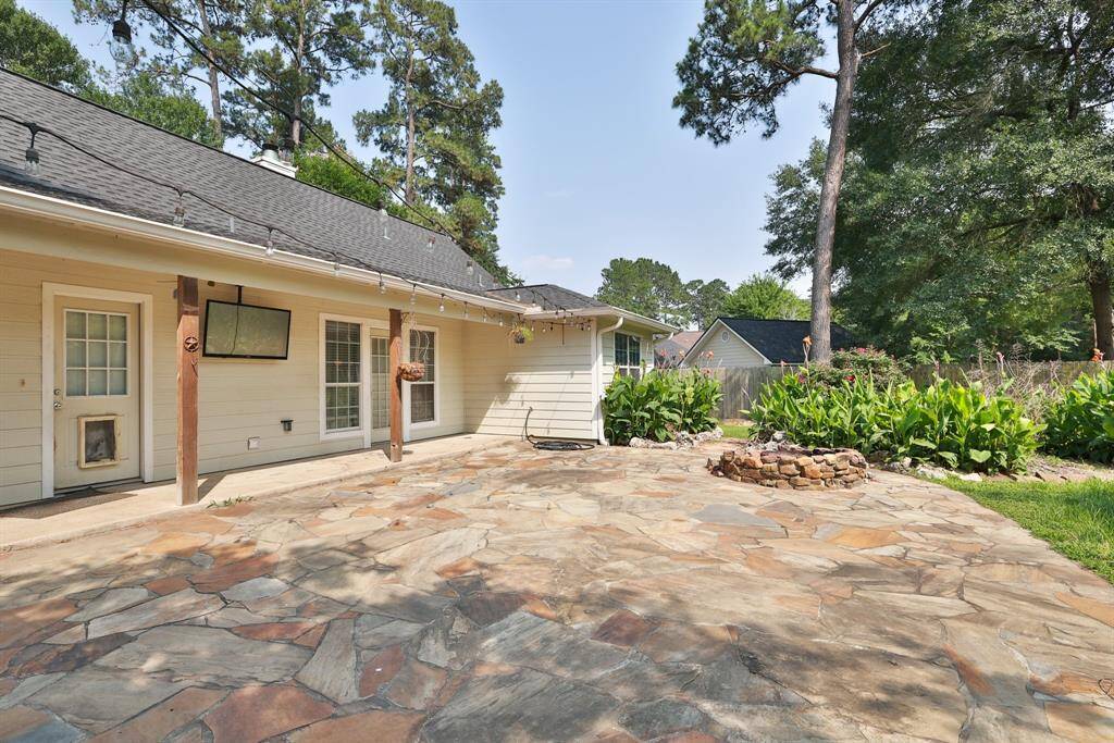 Spacious backyard with lush green lawn, mature trees, and a wooden fence providing privacy. Ideal for outdoor activities and relaxation.