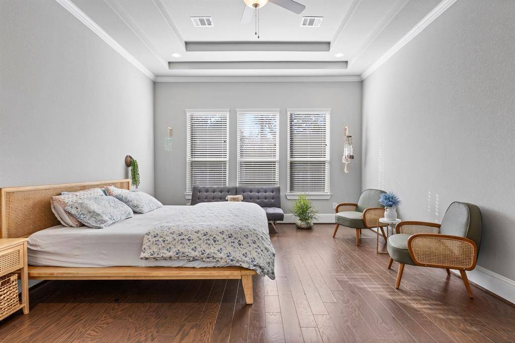 Wood Floors, Double Tray Ceiling, and Abundant Natural Light Illuminate the Primary Suite