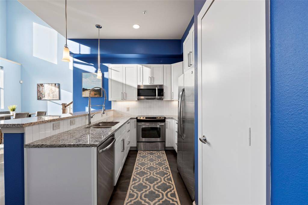 Open, galley shaped kitchen with new countertops, new cabinetry, and newly tiles backsplash to brighten your day