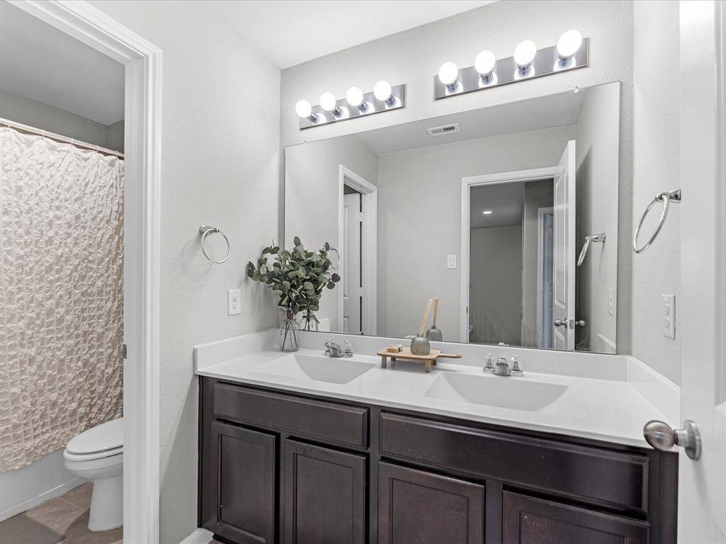 Secondary full bathroom features includes dual sinks and privacy door to the shower/tub and toilet.