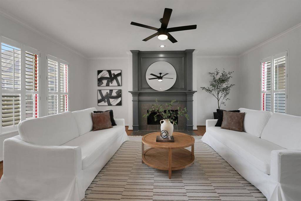 Bathed in natural light, the spacious living room features a wall of windows and a stunning fireplace that anchors the space with warmth and style