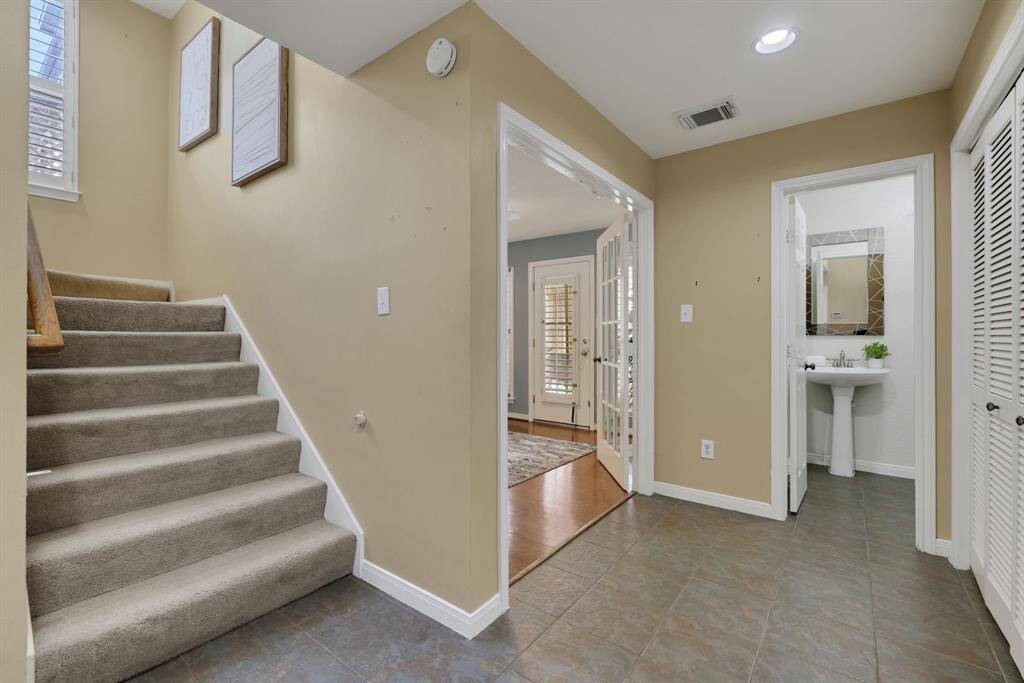 A sleek transitional space showcasing the stairway, powder bathroom and French door entry into the office effortlessly connecting the home’s main areas