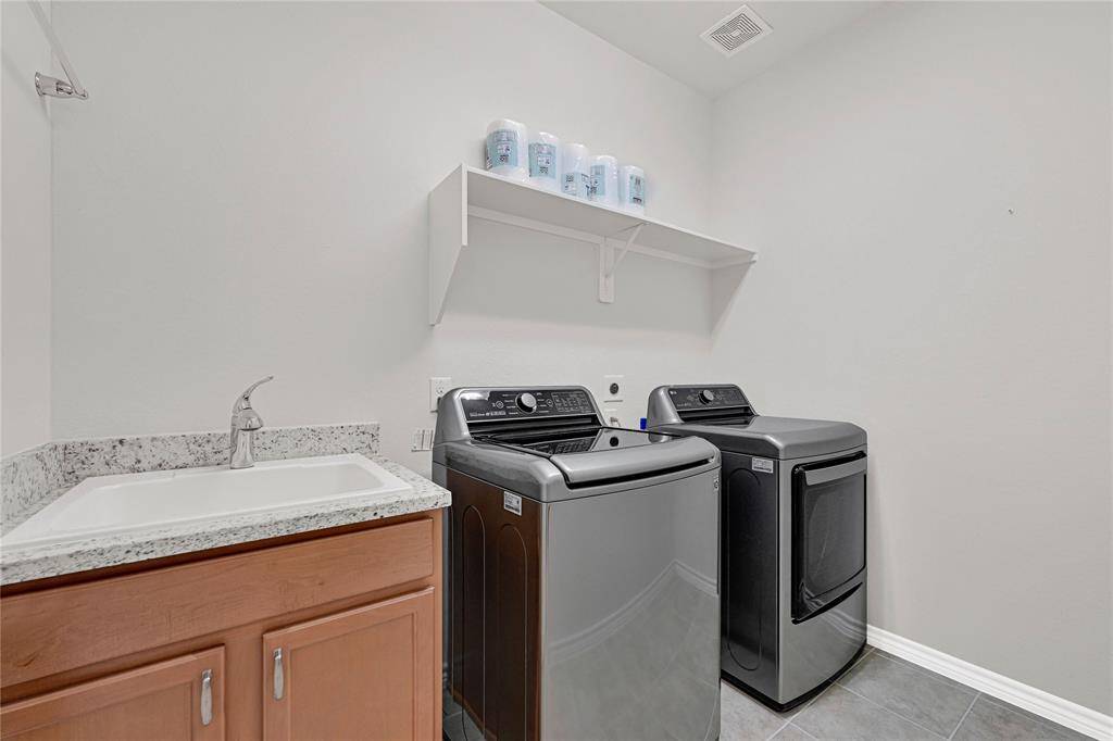 Functional Laundry Room – Equipped with a sink and additional cabinets for storage