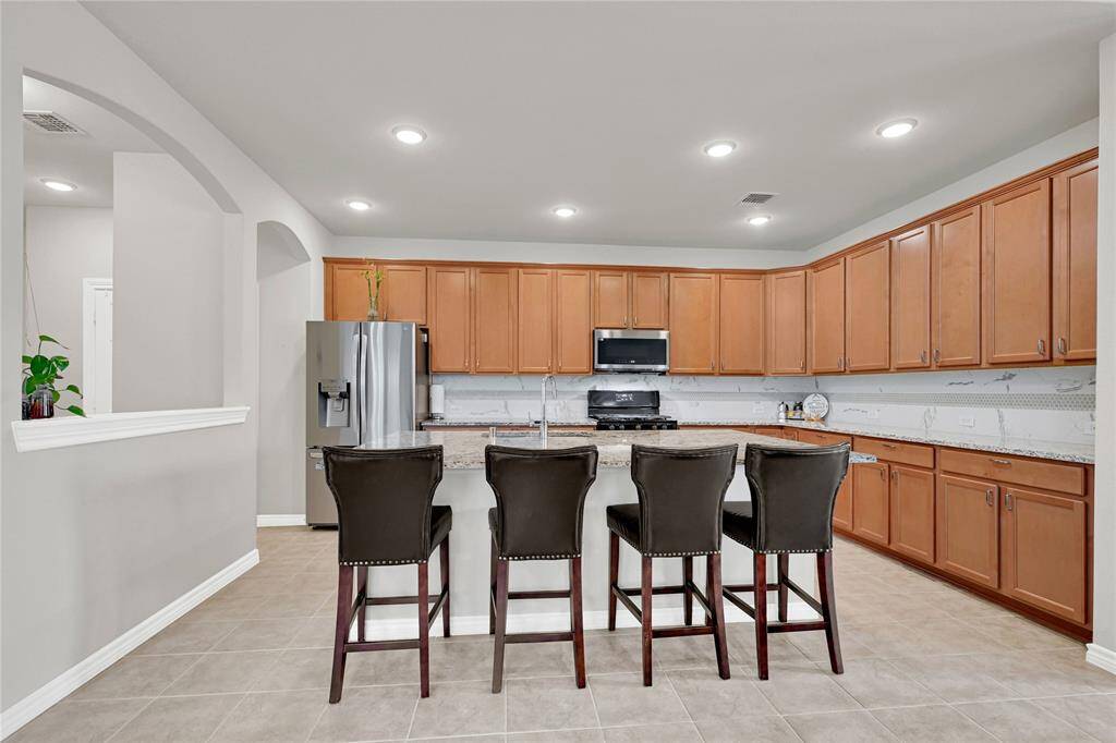 Chef’s Dream Kitchen – Ample cabinetry, gleaming granite countertops, and a large island with breakfast seating