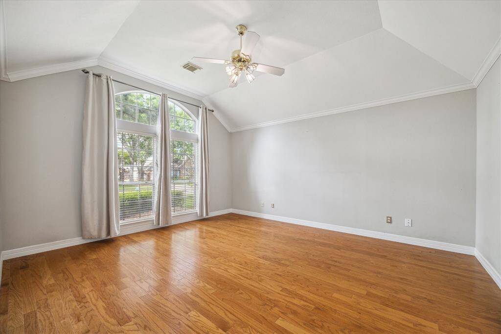 A wall of arched windows fills the primary bedroom with natural light and offers peaceful views of the front yard.