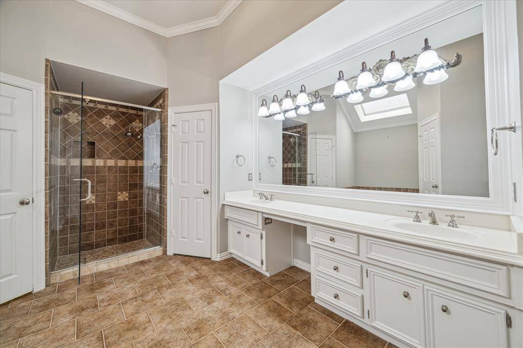 The ensuite bath includes a fully tiled walk-in shower, expansive dual vanities, and plenty of storage to keep everything organized.