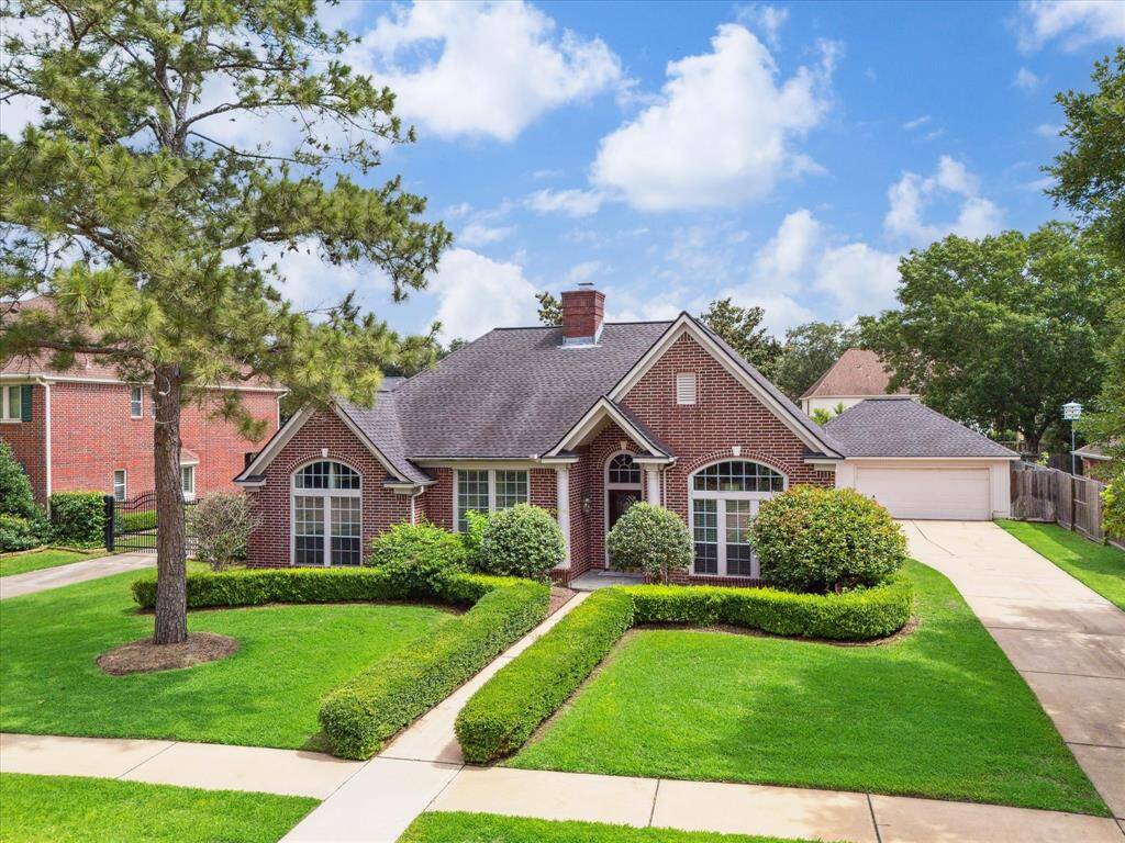 A sweeping driveway leads to a detached 2-car garage, complementing the home’s charming curb appeal and lush, manicured landscaping.
