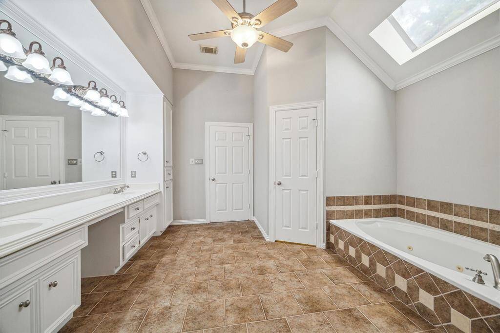 A vaulted ceiling with a large skylight bathes the space in natural light, perfectly illuminating the jetted soaking tub and creating a relaxing, spa-like atmosphere.