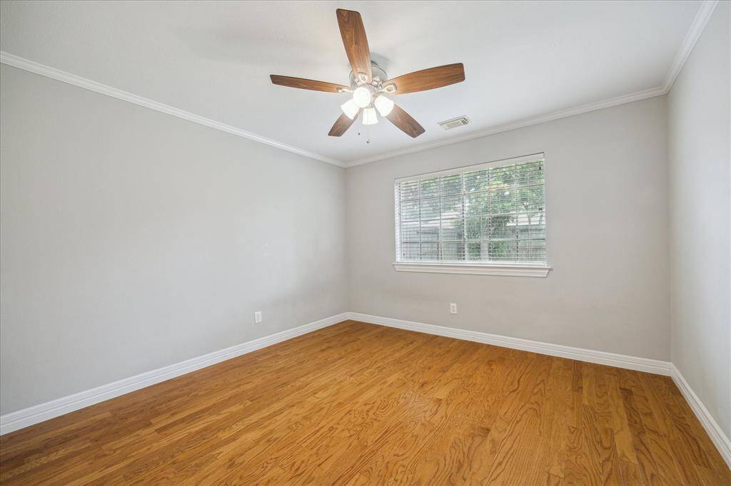 This secondary bedroom offers a peaceful atmosphere with soft neutral tones, a large window, and a modern ceiling fan.