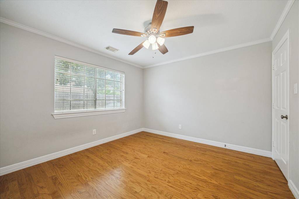 The third bedroom provides ample room for rest or study, complemented by warm wood flooring and crown molding.