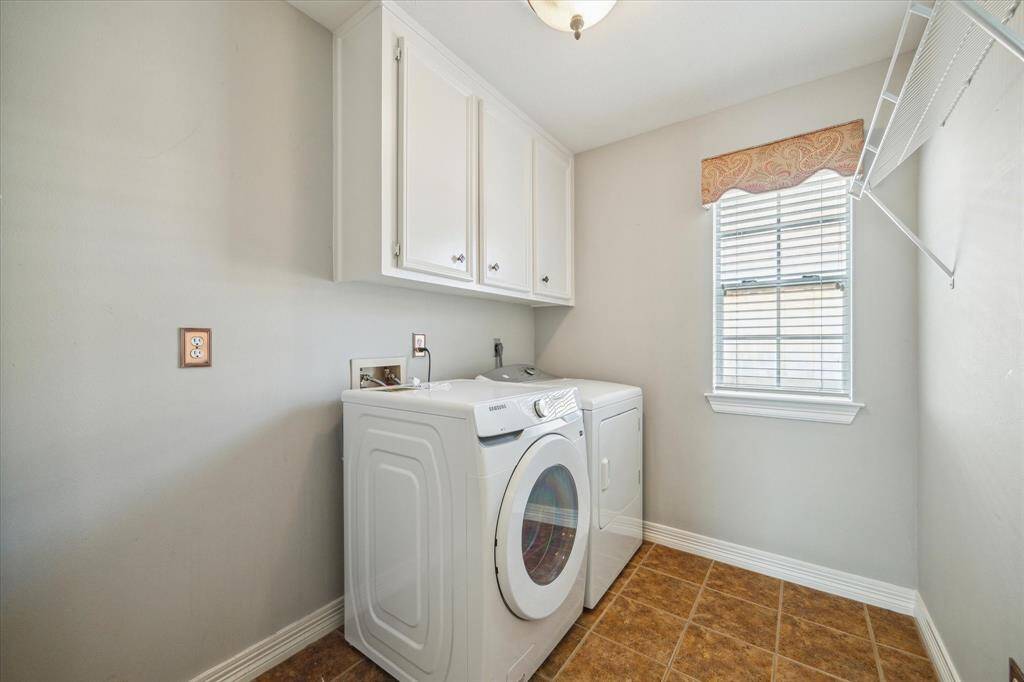 The spacious laundry room includes upper cabinetry for extra storage and a window for natural light.