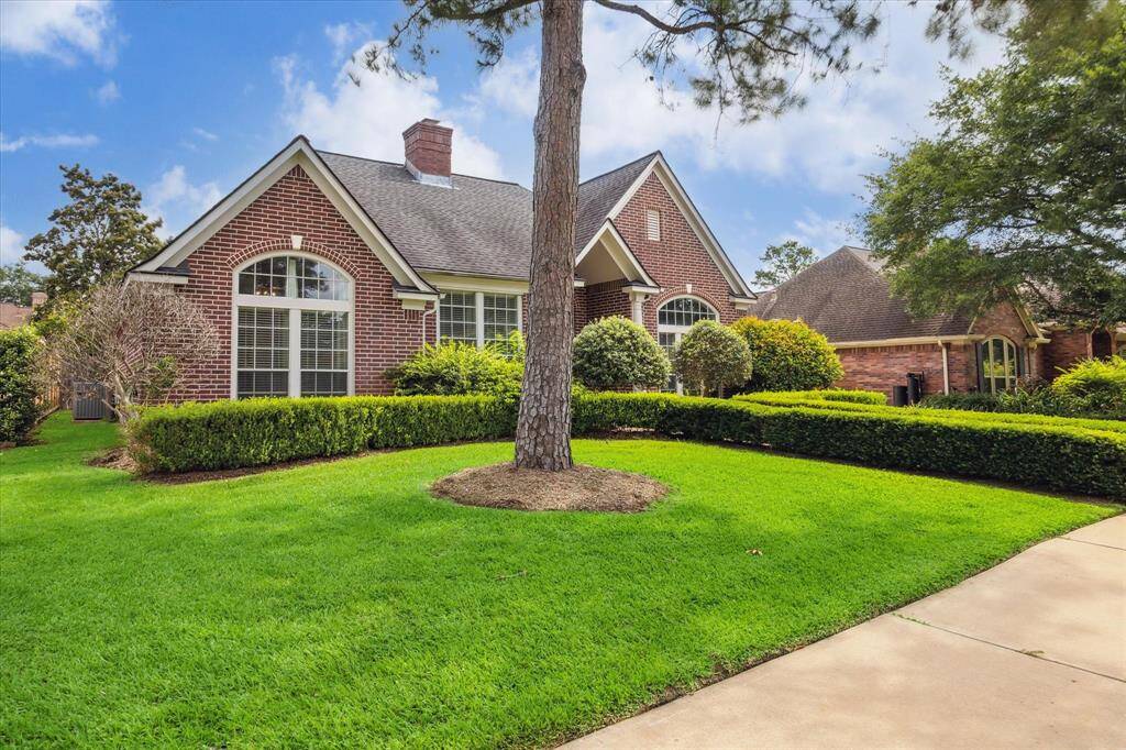 Crisp landscaping and mature trees frame this brick beauty, highlighting its timeless architecture and serene front yard setting.