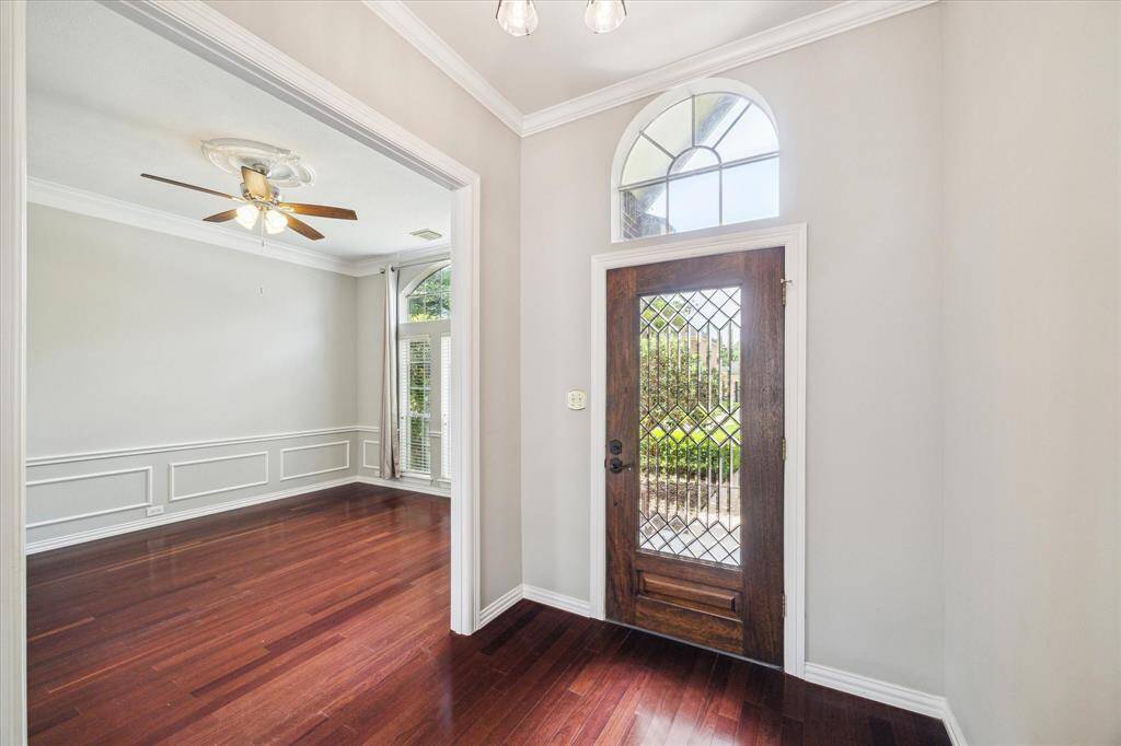 The entryway sets the tone with a custom wood and glass front door, elevated ceilings, and arched transom window that fills the space with natural light.