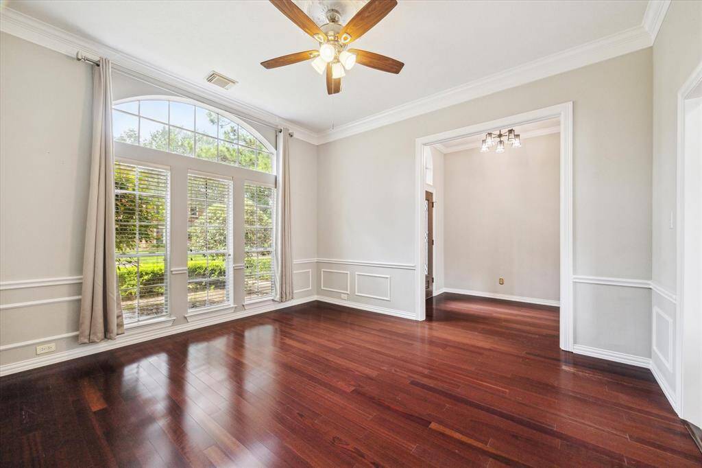 Sunlight pours into the dining room through tall arched windows with a view of the beautifully landscaped front yard.
